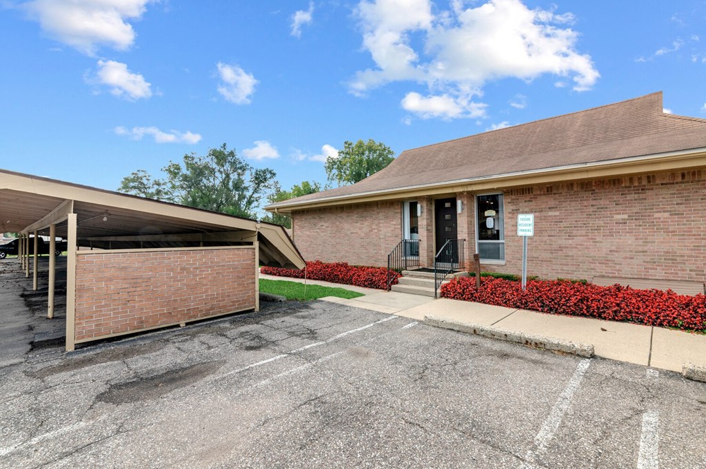 the front of a brick building with a driveway and a parking lot