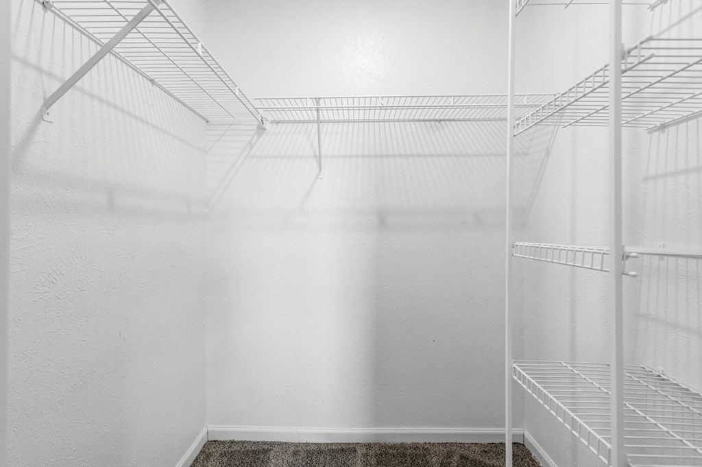 a walk in closet in a bedroom with white walls