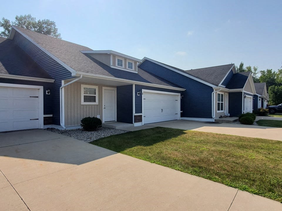 a blue house with white doors and a driveway