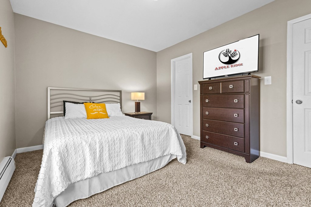 a bedroom with a bed and a dresser at Apple Ridge Apartments - Livonia, MI, Livonia, MI