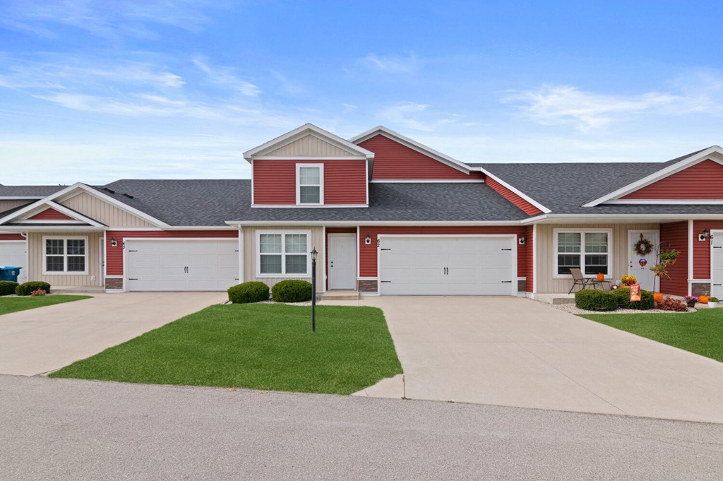 a red house with a driveway and a lawn in front of it