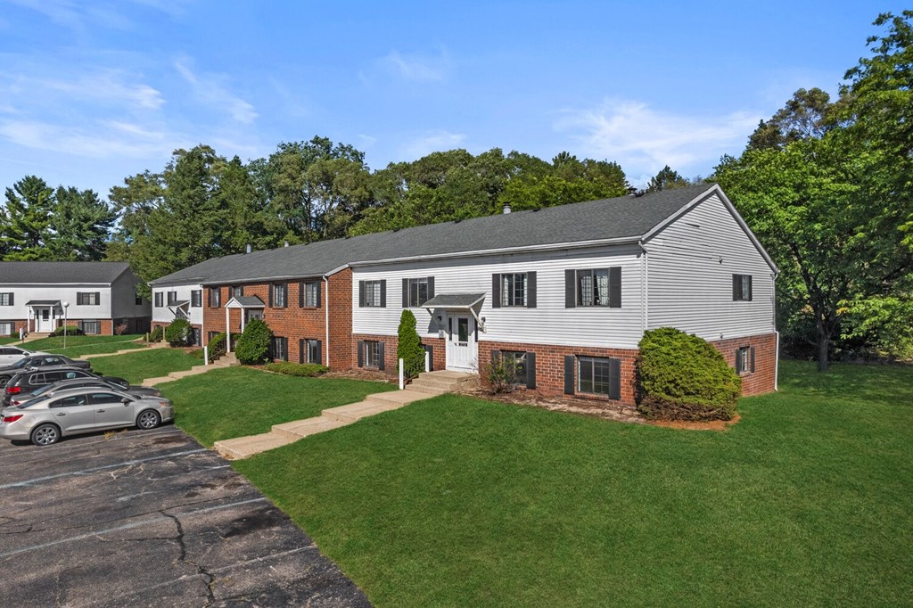 a white house with a yard and a parking lot