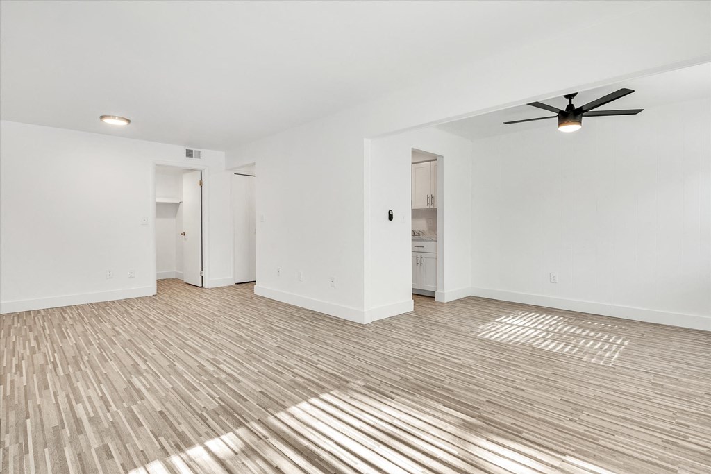 an empty living room with white walls and a ceiling fan