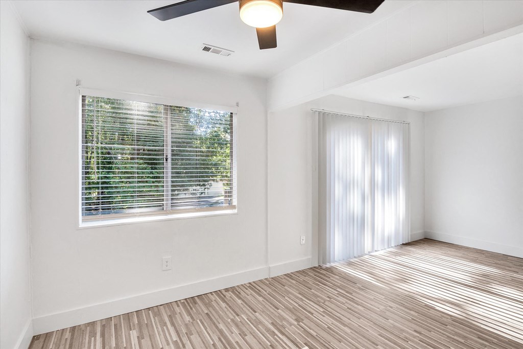 an empty living room with a window and a ceiling fan