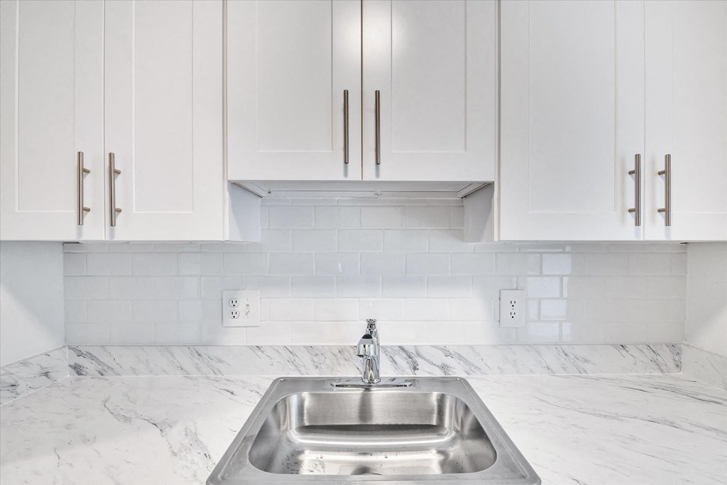 a white kitchen with a stainless steel sink and white cabinets