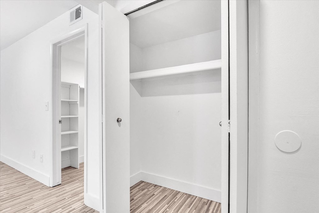 a bedroom with white walls and a closet with shelves
