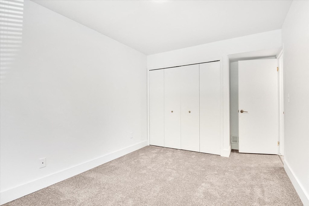 a bedroom with white walls and white closet doors