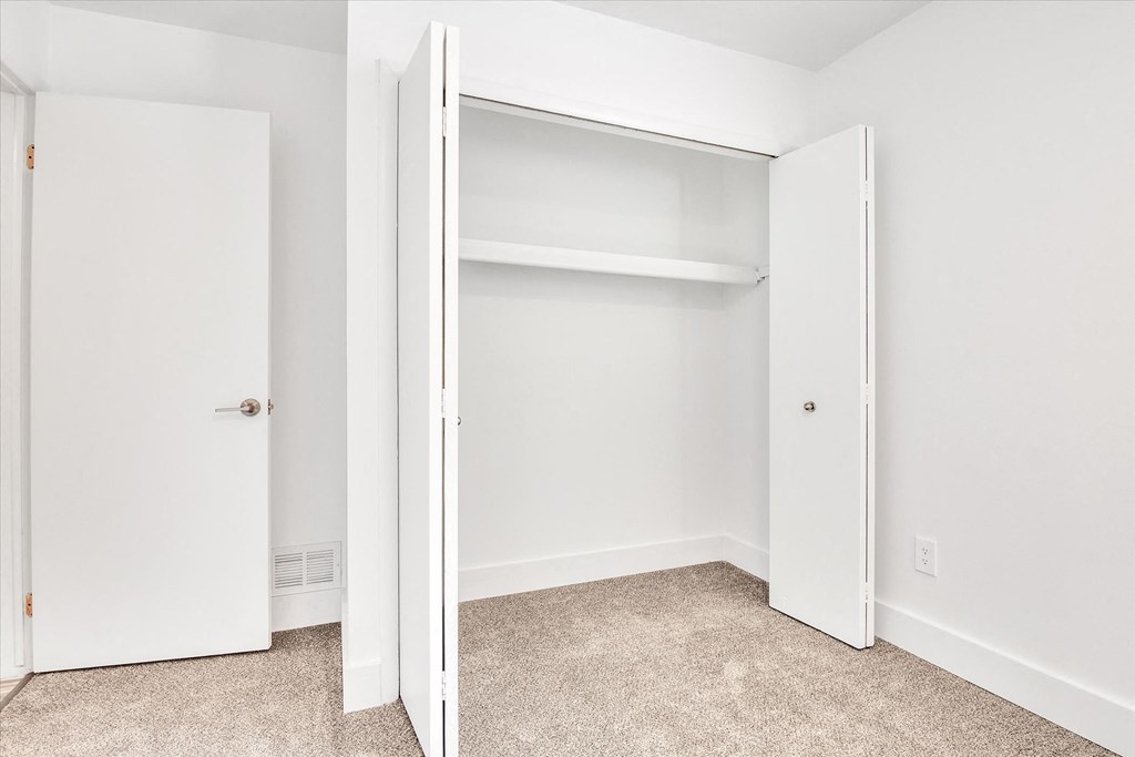 a bedroom with an open closet and a carpeted floor