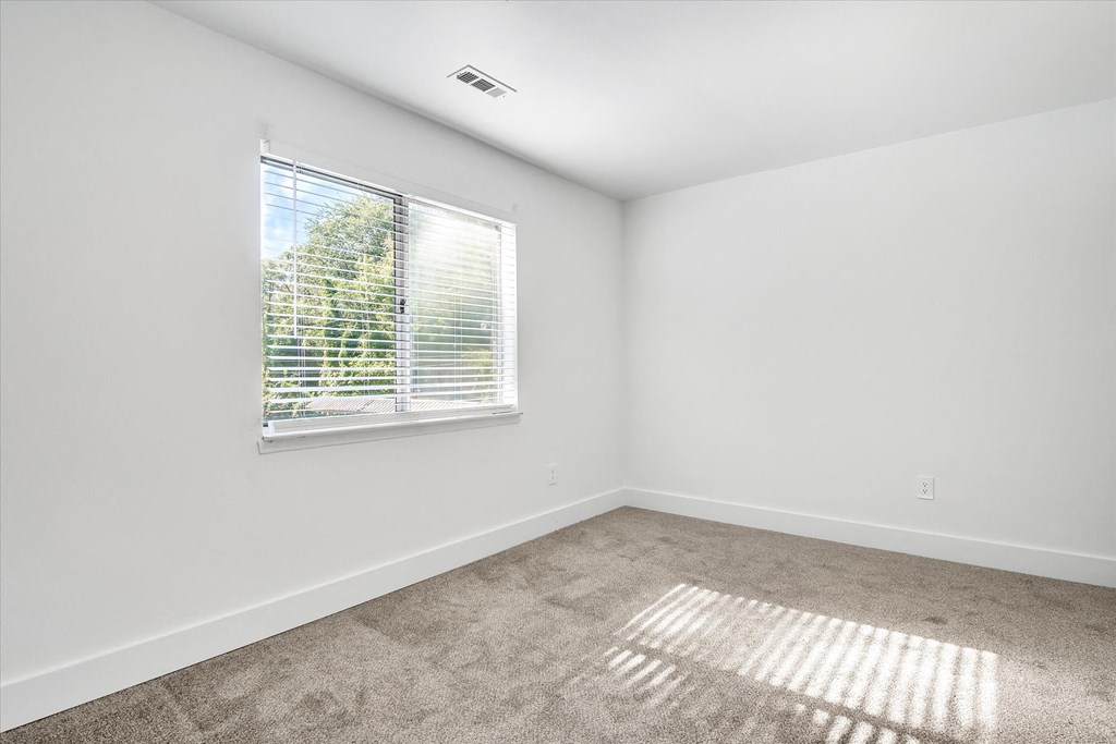 an empty room with a window and carpet