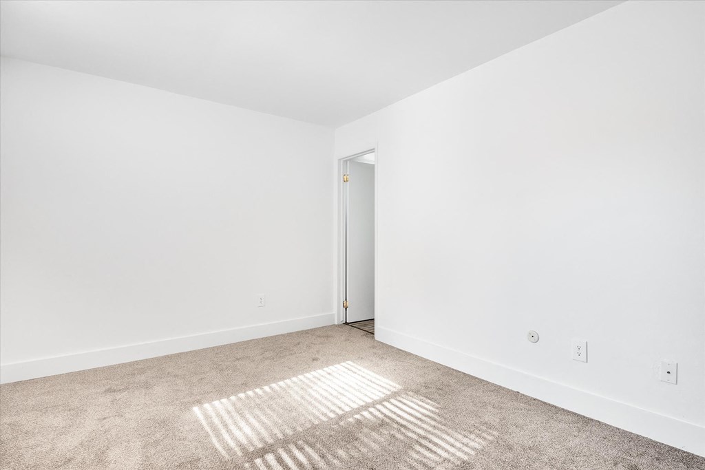 a room with white walls and carpet and an open door