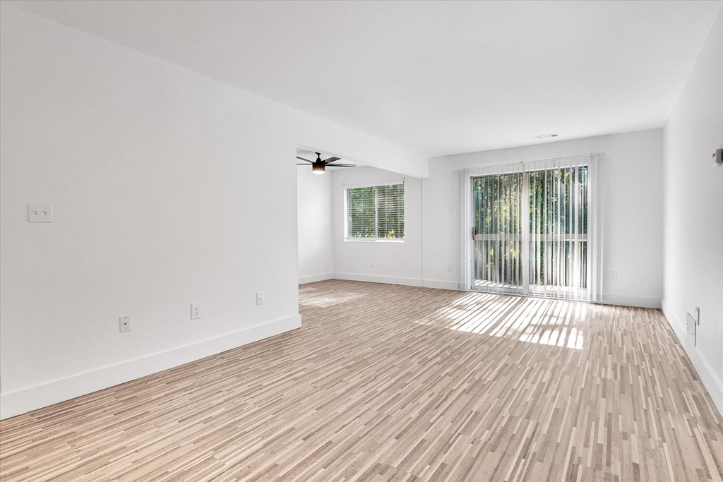 the living room and dining room of an empty house with wood flooring