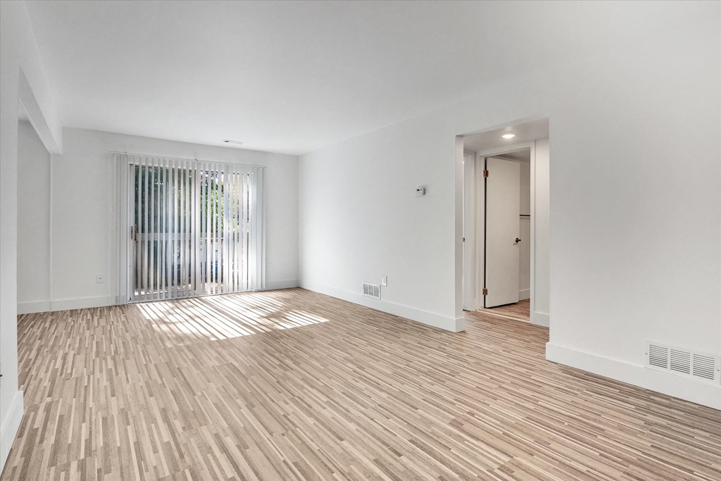 the living room and entryway of an apartment with wood flooring