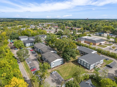 A bird's eye view of a parking lot surrounded by buildings and trees.