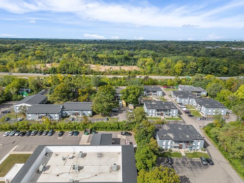 A bird's eye view of a parking lot and buildings surrounded by trees.
