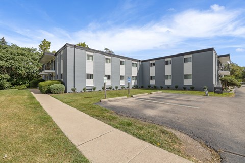 A large grey building with a parking lot in front.