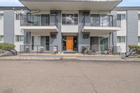 A modern apartment building with a grey facade and a central orange door.