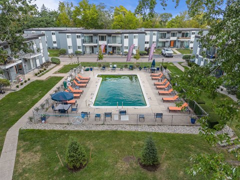 A swimming pool surrounded by chairs and umbrellas in a grassy area.