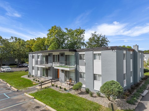A modern apartment building with a parking lot in front.
