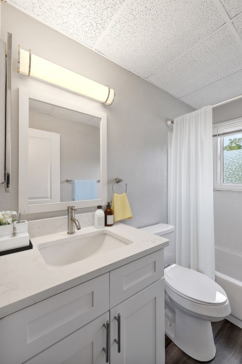 A white bathroom with a sink, toilet, and mirror.