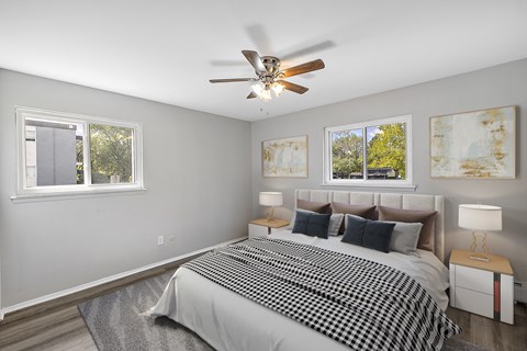 A bedroom with a bed, two lamps, and two paintings on the wall.