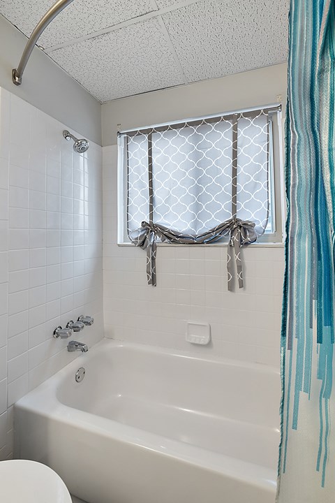 A white bathtub with a shower curtain tied in a bow.