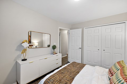 A white bedroom with a bed, dresser, and mirror.