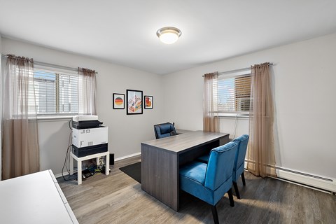 A room with a desk, chair, and a pile of books.