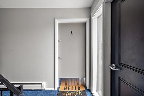 A black door with a mat that says "HELLO" on it.