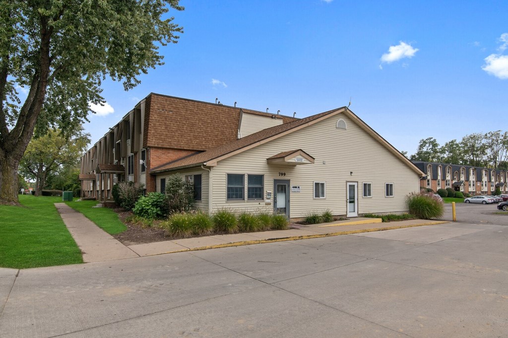 a white building with a brown roof next to a sidewalk