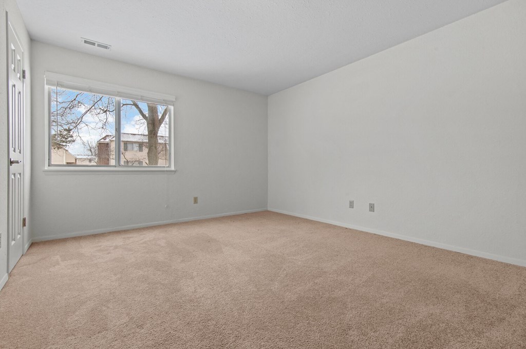 an empty living room with a window and carpet