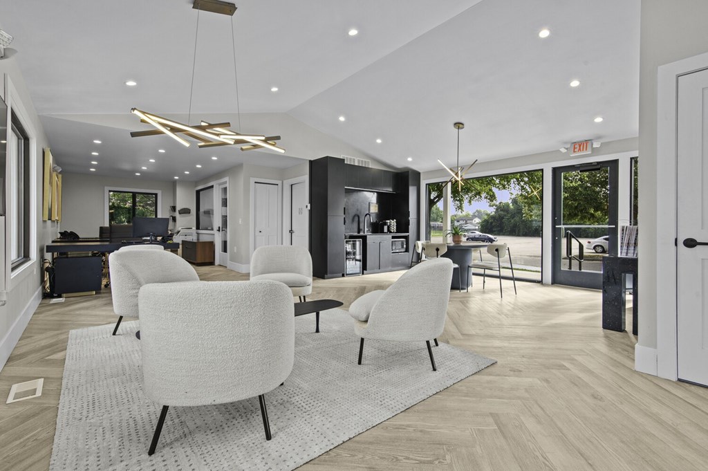 A modern living room with white chairs and a grey rug.