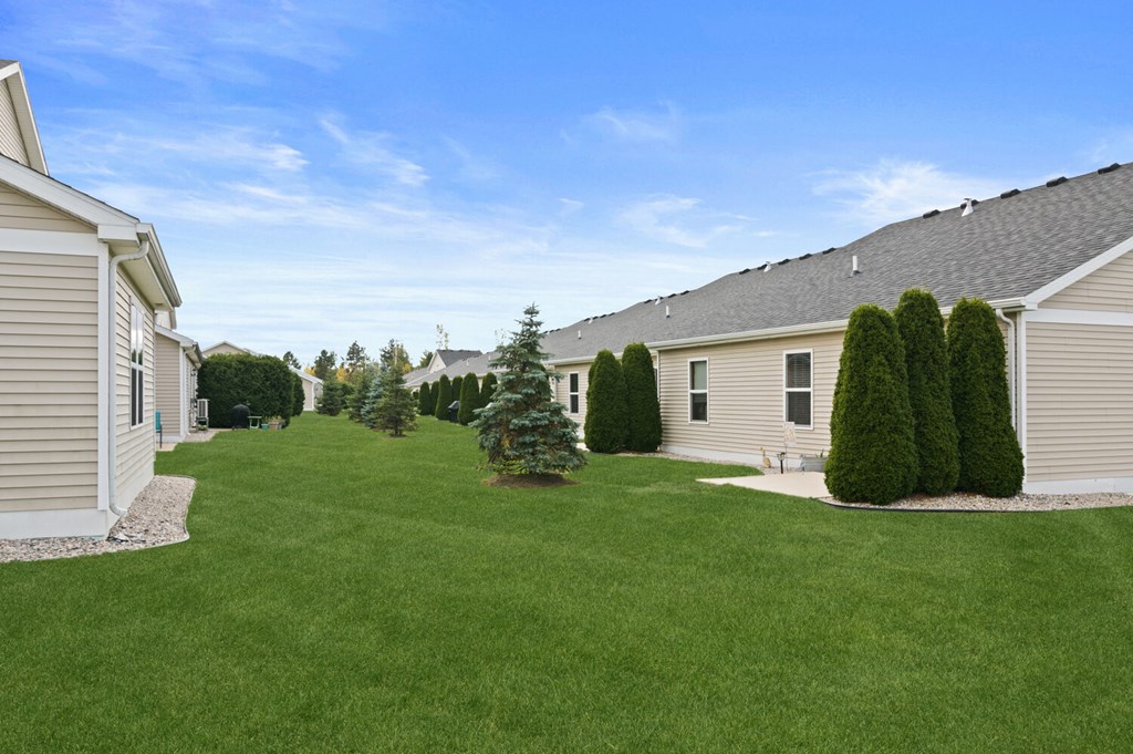 the backyard of a house with a lawn and trees