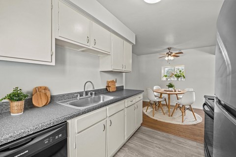 A kitchen with white cabinets and a black dishwasher.