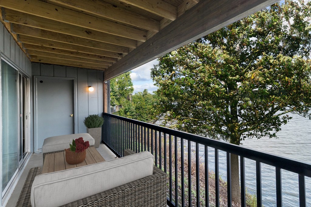 A balcony with a couch and a view of the water at The Waverly on the Lake - Belleville, MI Apartment, Belleville, MI, 48111