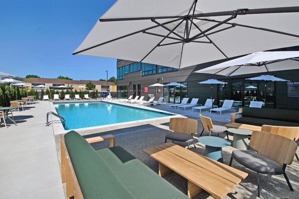 A pool area with sun loungers and umbrellas.