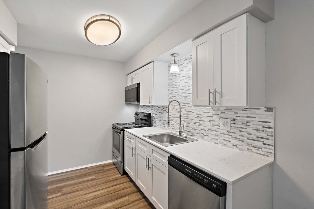 a renovated kitchen with white cabinets and a stainless steel refrigerator