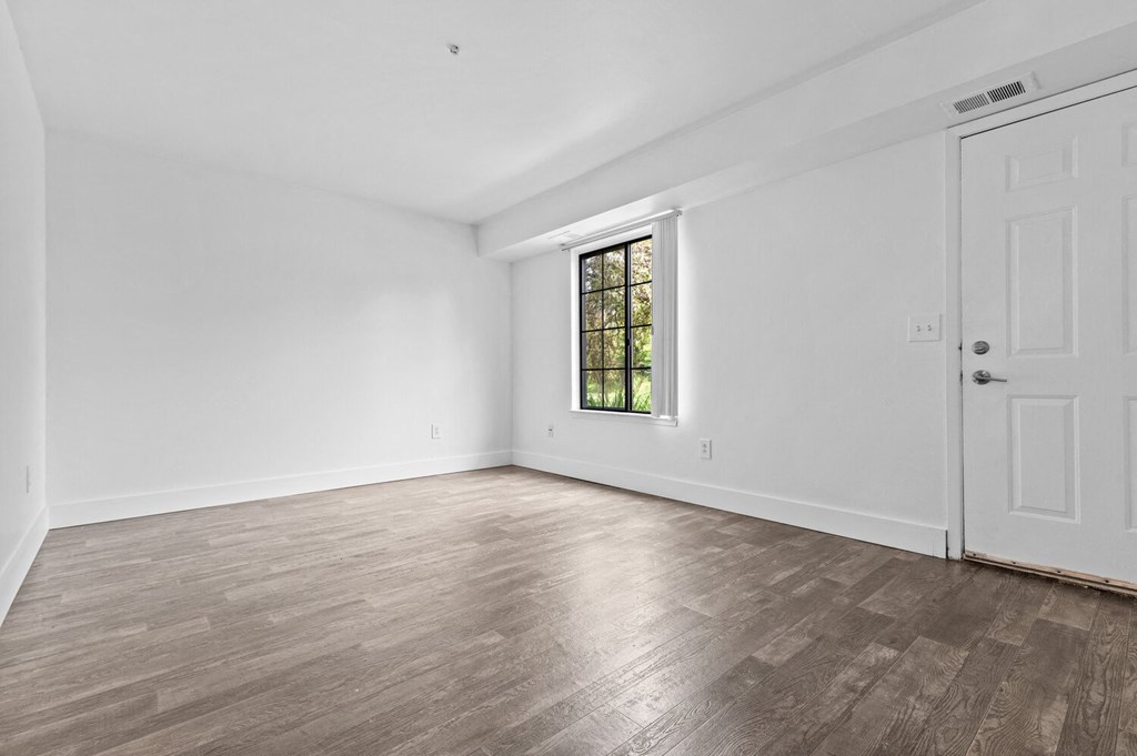 a bedroom with hardwood floors and white walls