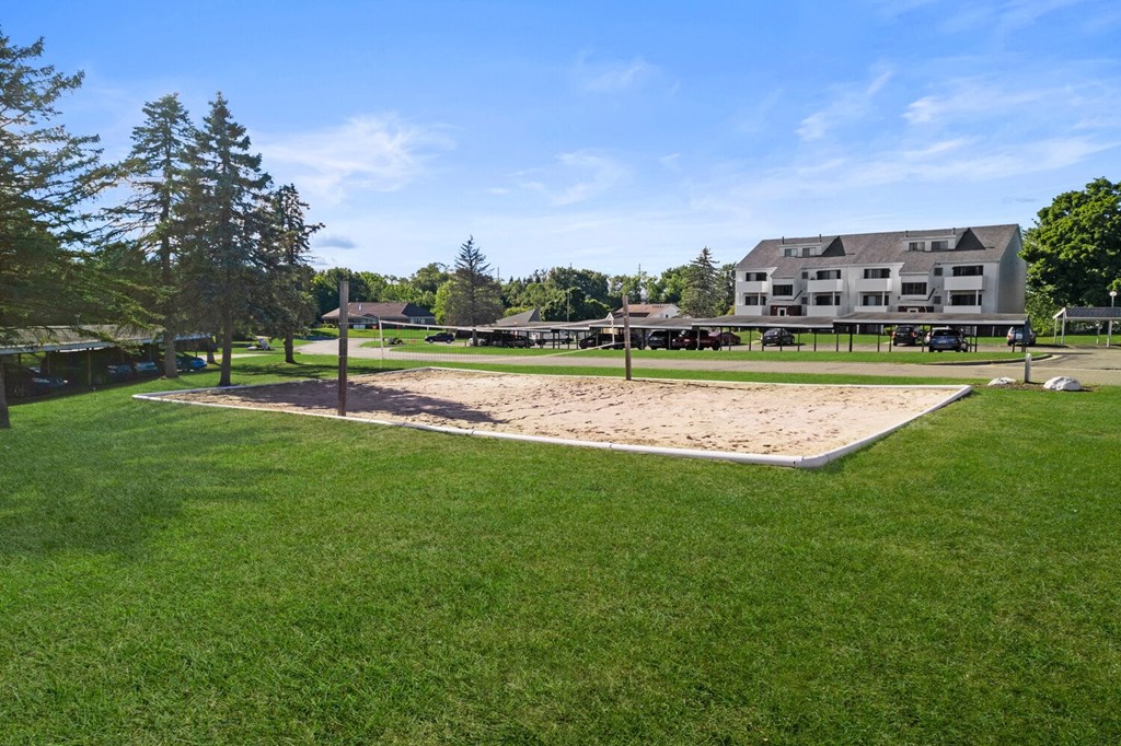 a sand volleyball court in a park with a house in the background