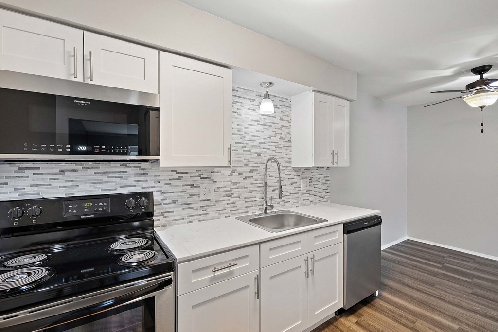 a kitchen with white cabinets and black appliances