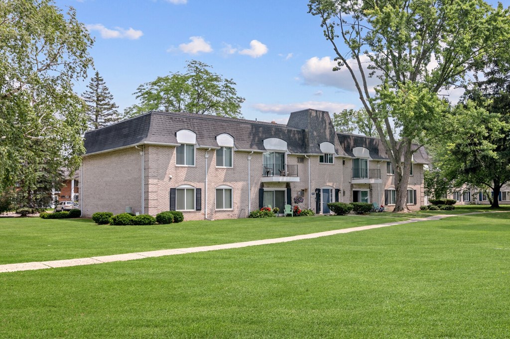 a large brick building with a green lawn in front of it at Apple Ridge Apartments - Livonia, MI, Livonia