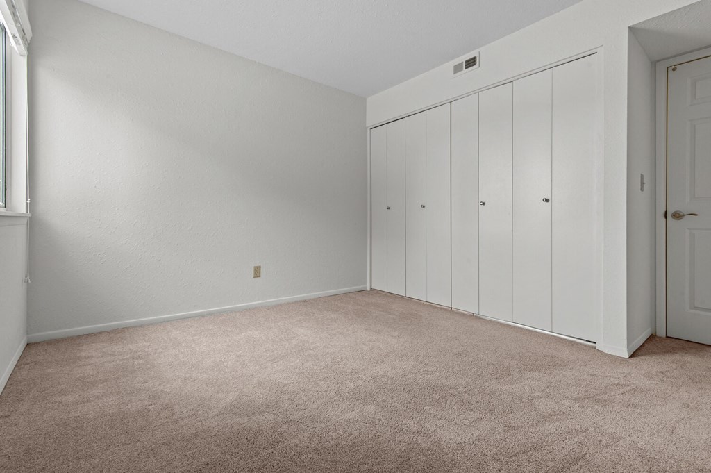 an empty room with white closet doors and carpet