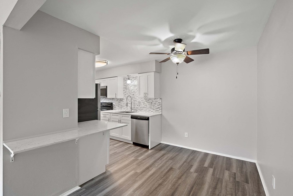 a living room with a ceiling fan and a kitchen