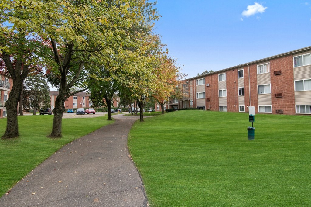 a pathway leading through a green lawn in front of an apartment building