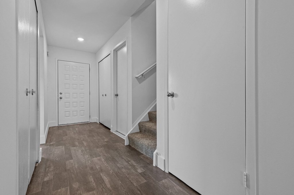 the landing of a staircase in a home with white walls and wood floors at Edge At Farmington Hills - Farmington Hills, MI, Michigan, 48334