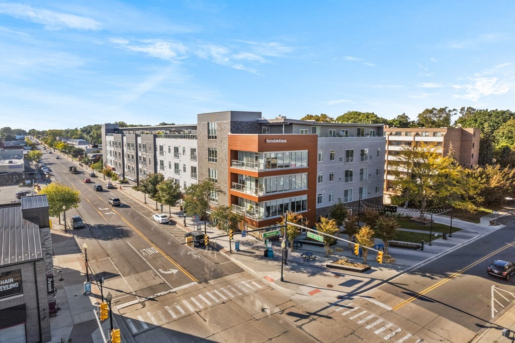 an aerial view of an apartment complex with a street in the foreground and trees in the background