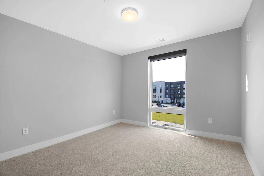 A room with a window that has a view of a cityscape.