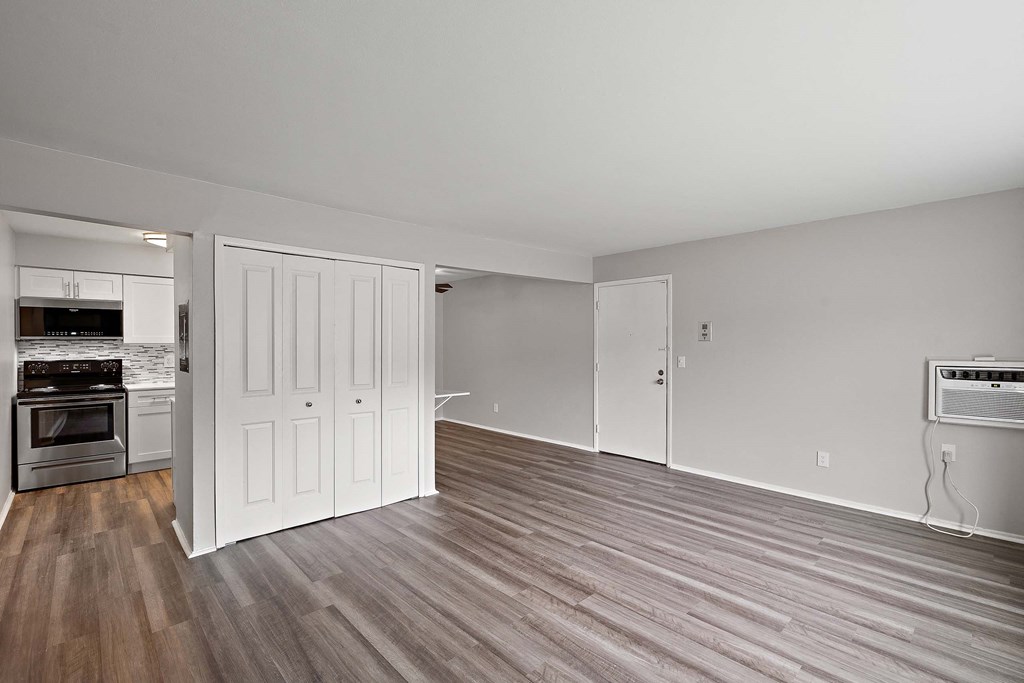 the living room and kitchen of an apartment with wood flooring