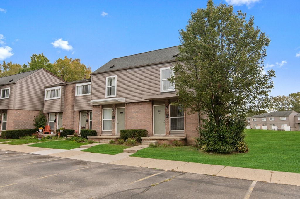 a brick apartment building with a sidewalk and grass