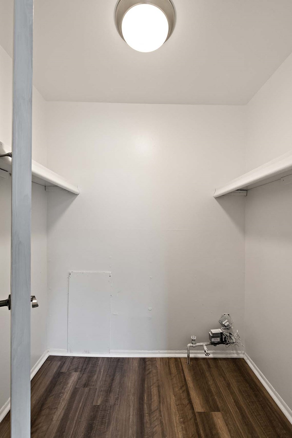 a room with white walls and wooden floors and a white closet