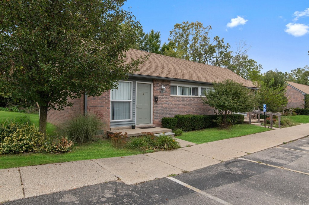 a small brick house with a sidewalk in front of it